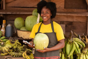 A-woman-at-the-market-holding-watermelon-in-her-fruit-shop-smiling